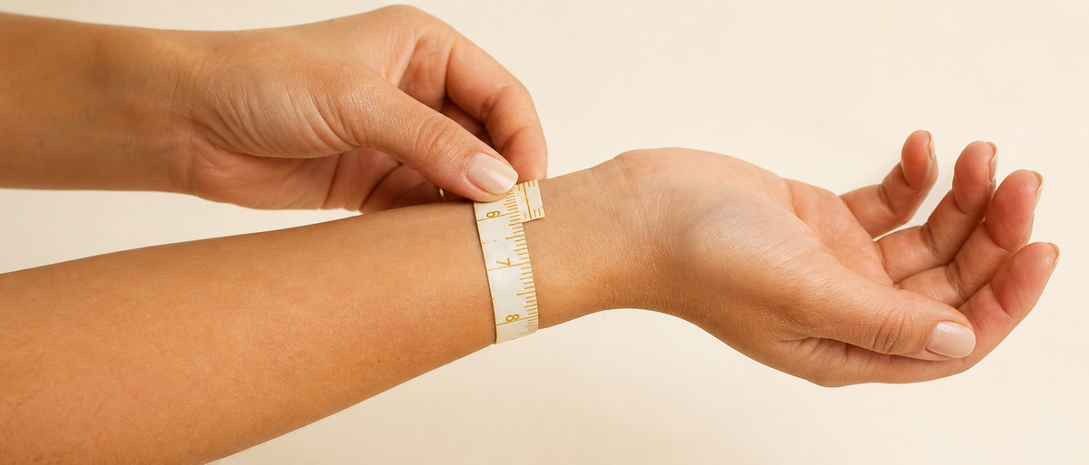 Hands wrapping a measuring tape snugly around the wrist above the wrist bone