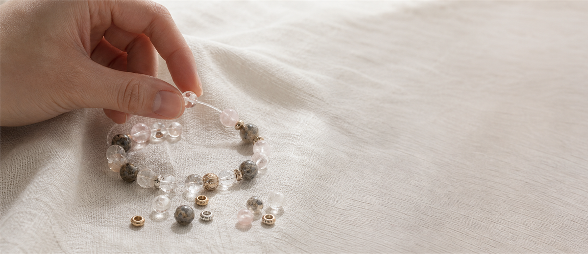 Hands assembling a custom crystal bracelet on natural linen
